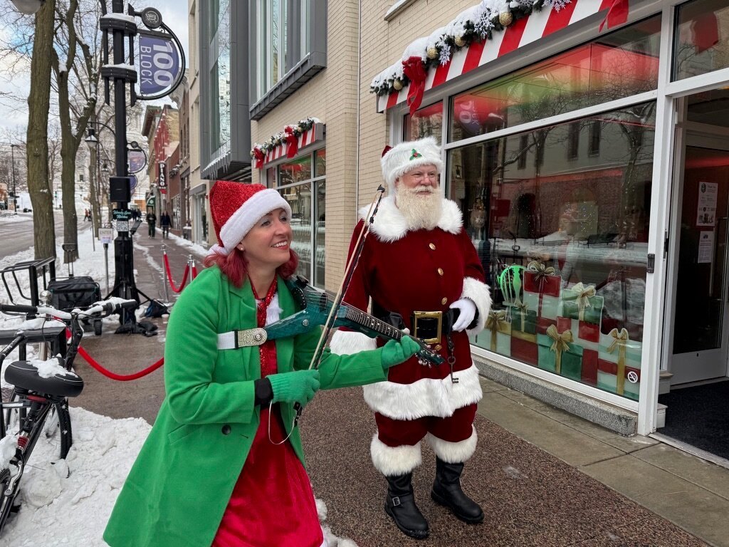 Santa walking down State Street with a violin-playing elf