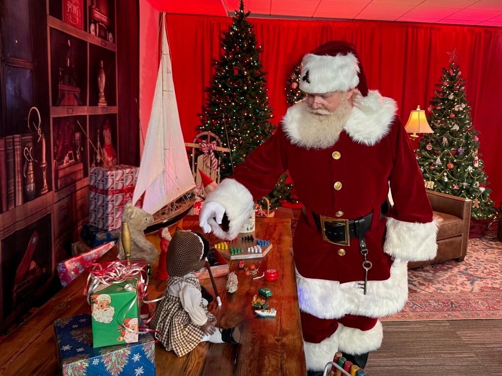 Santa looking over a table of toys in his workshop